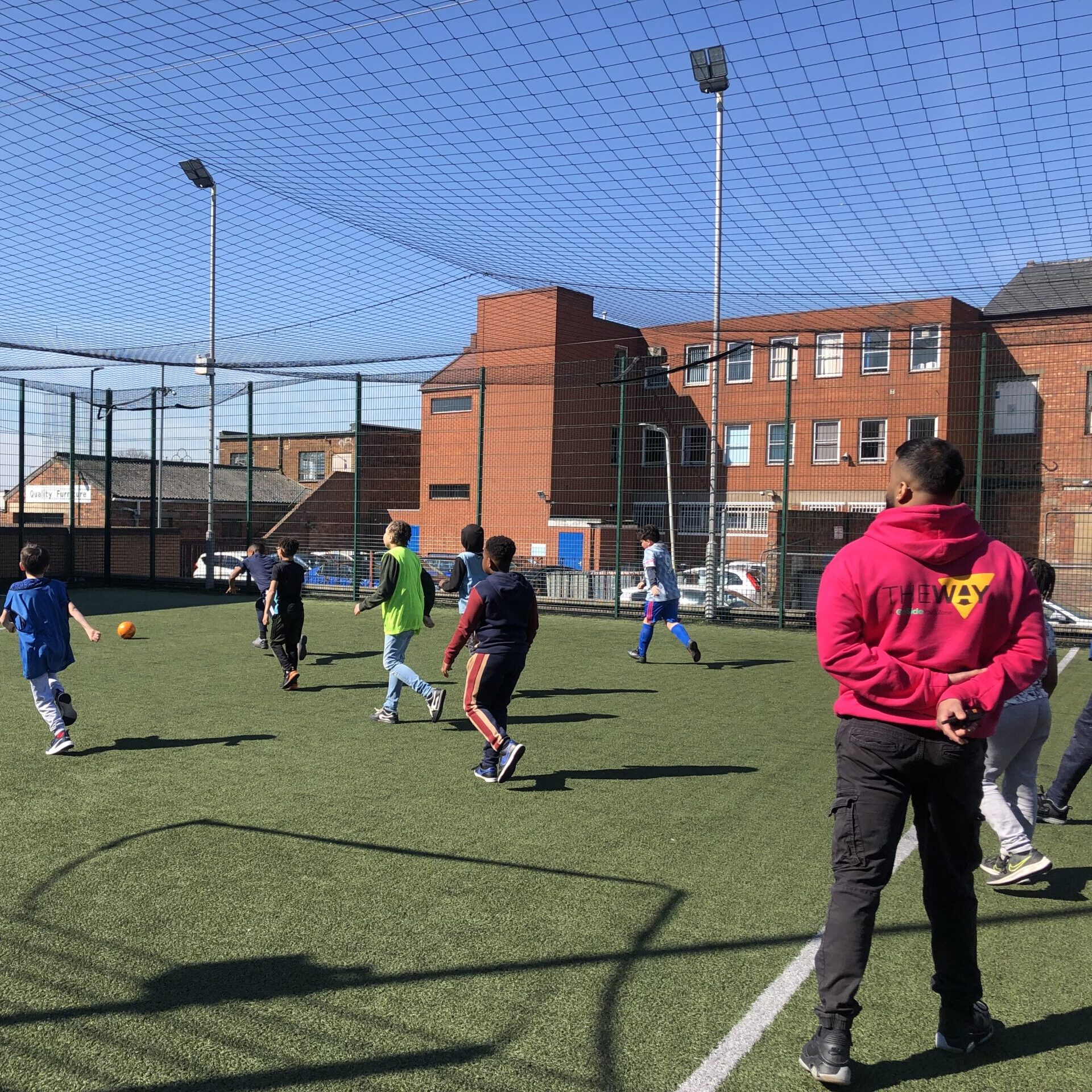 A member of our youth team supervising a game of football on the outdoor pitch