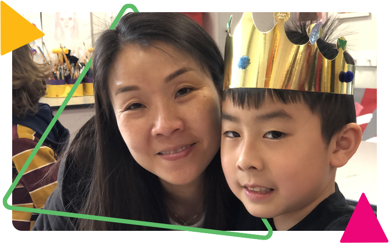 A boy and his mum smiling together. The boy is wearing a gold cardboard crown.