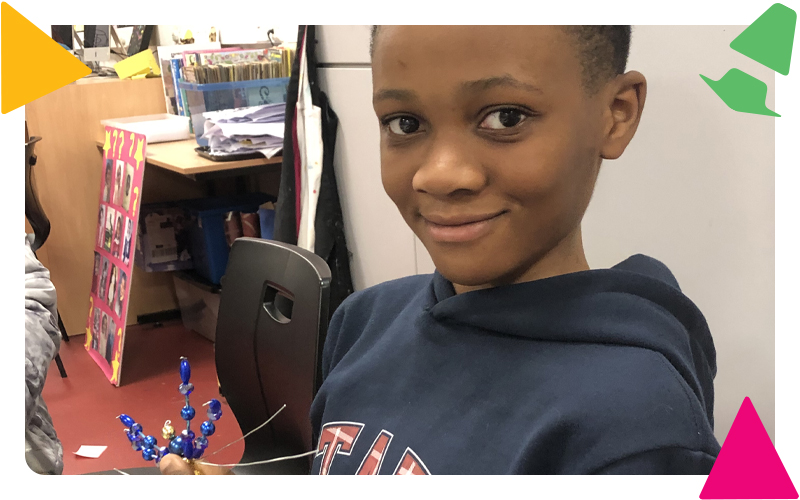 A young boy making a decorative spider from wire and shiny beads