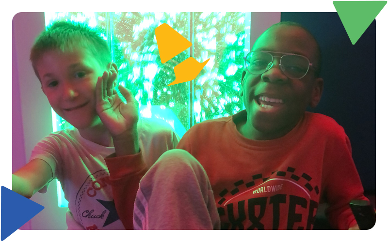 Two boys sitting together, smiling in the sensory room