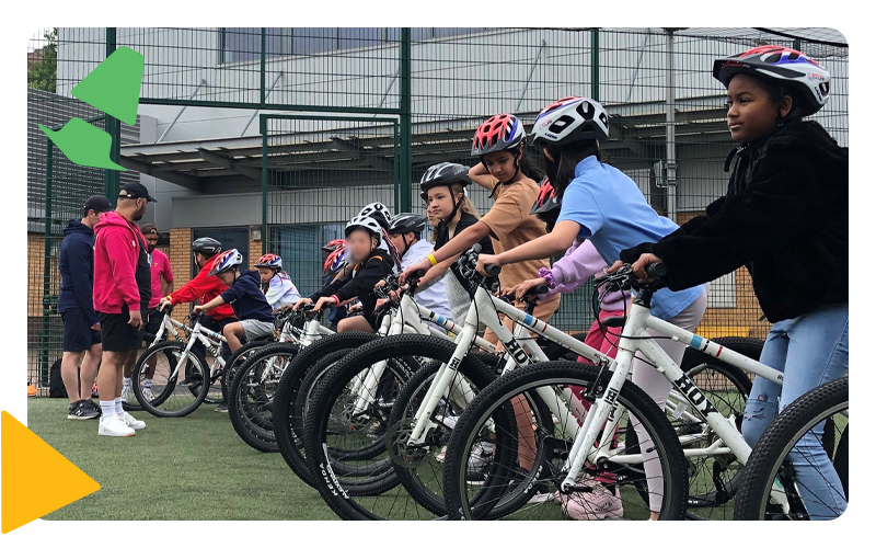 A group of young people in a line on bicycles wearing cycling helmets