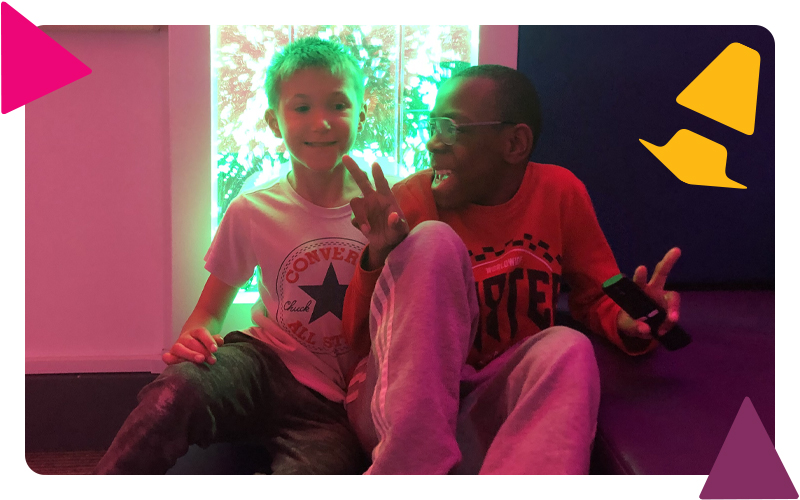 Two boys sitting together, smiling in the sensory room